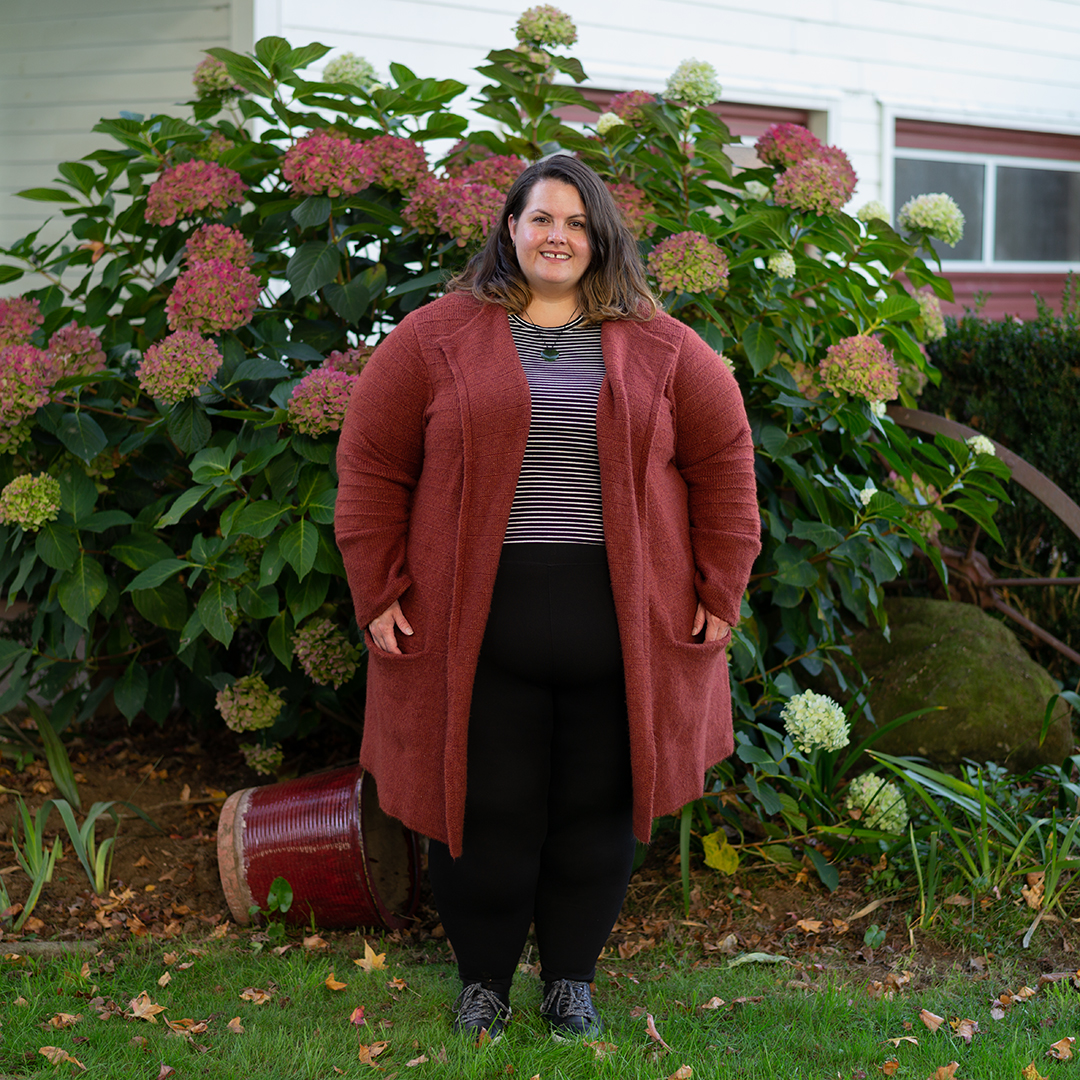 New Zealand plus size blogger Meagan Kerr stands in front of a hydrangrea bush. She wears City Chic Cheeky Stripe Top in XXL, Snag Tights Leggings in H, Old Navy Rust Cardigan in 4X and Ziera Shoes DANNI sneakers in 8