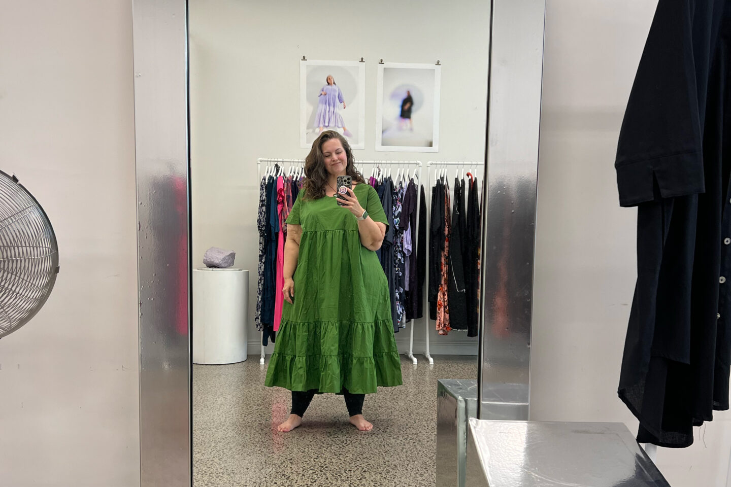 A mirror selfie of Meagan in the Lost and Led Astray store. She is wearing a leaf green dress and black compression leggings.